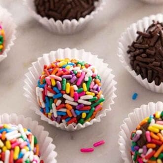 Multiple brigadeiros with colorful and chocolate sprinkles coating them.