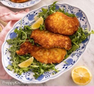 Pinterest graphic of a platter of chicken Milanese over arugula salad with lemon wedges.