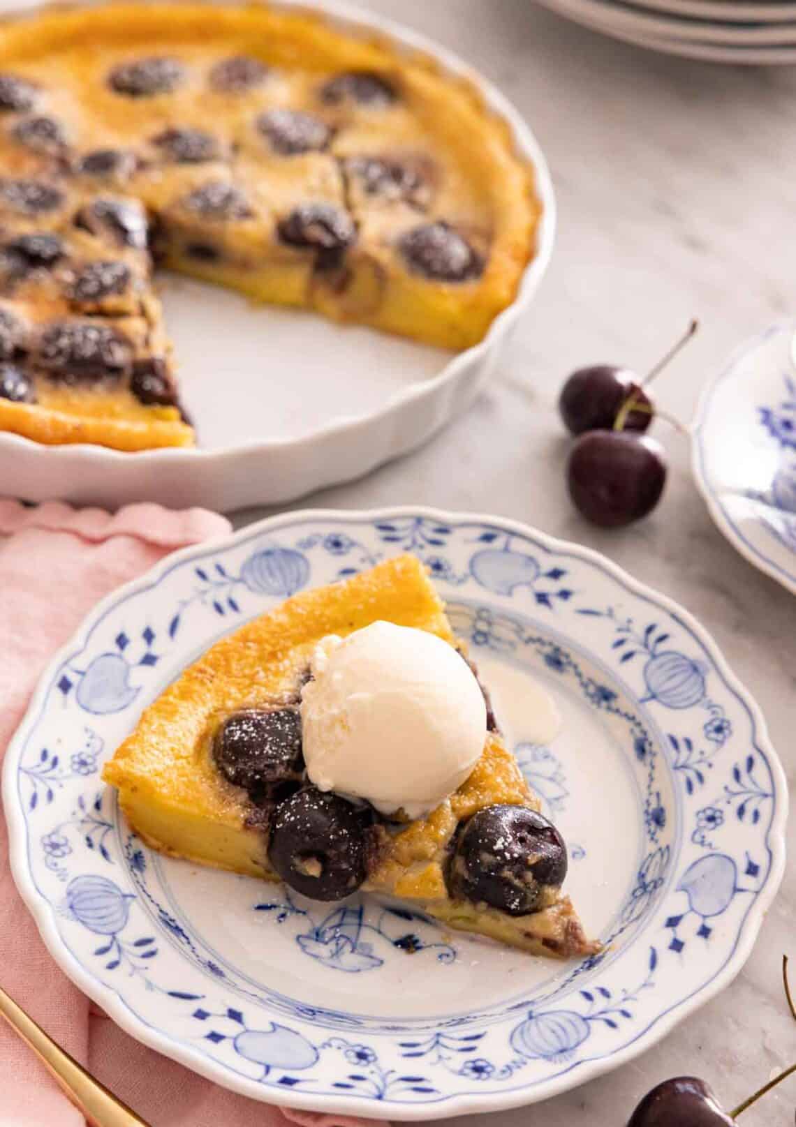 A slice of clafoutis on a plate with a scoop of ice cream on top.