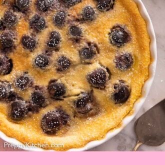 Pinterest graphic of an overhead view of a round baking dish of clafoutis with powdered sugar dusted on top.