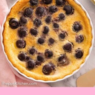 Pinterest graphic of clafoutis with cherries in a white round baking dish.