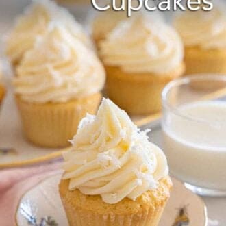 Pinterest graphic of a coconut cupcake on a small plate by a glass of milk and a platter of cupcakes.