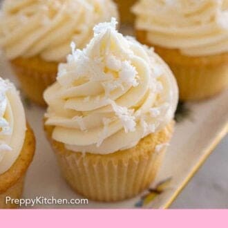 Pinterest graphic of a close up of coconut cupcake on a platter of cupcakes.