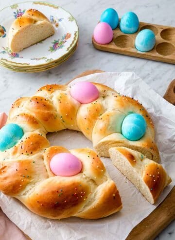 Easter bread with two slices cut out, one on a plate and the other near the entire bread.