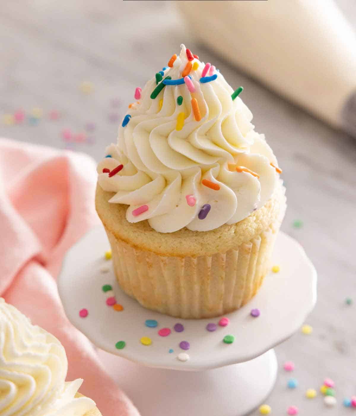 A vanilla cupcake with Italian buttercream piped on top with sprinkles.
