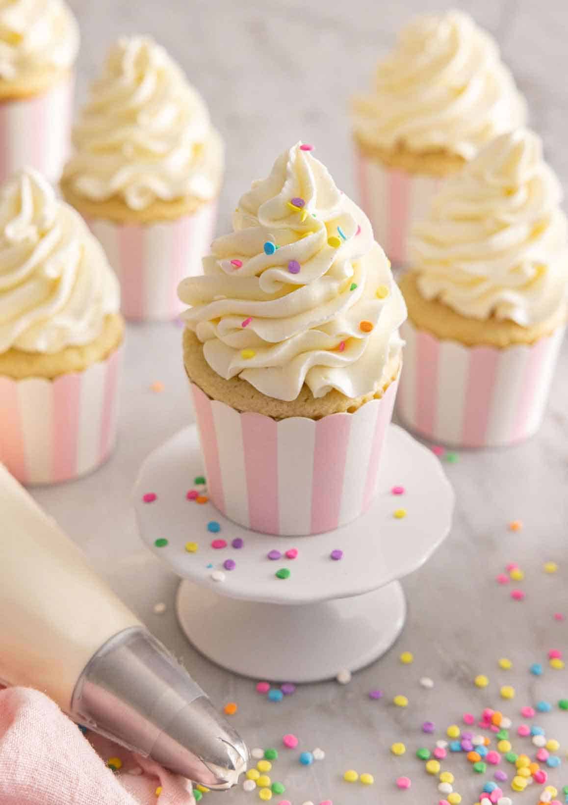 Multiple cupcakes with Italian buttercream piped on top with sprinkles.