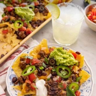 Pinterest graphic of a plate of nachos by a drink and sheet pan with more nachos.