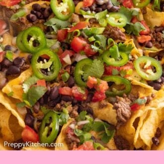 Pinterest graphic a close up view of nachos with fresh herbs and jalapeños on top.