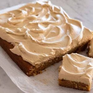 A peanut butter cake with two square slices cut, on a piece of parchment.