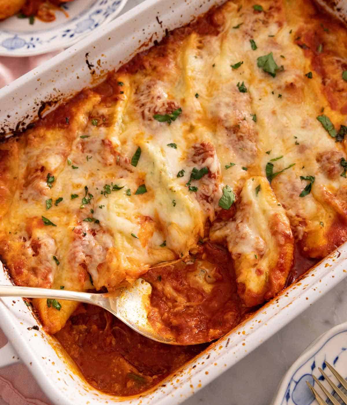 Overhead view of a baking dish with stuffed shells with a spoon inside.