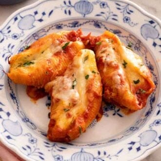 A plate of three stuffed shells with a fork beside it.