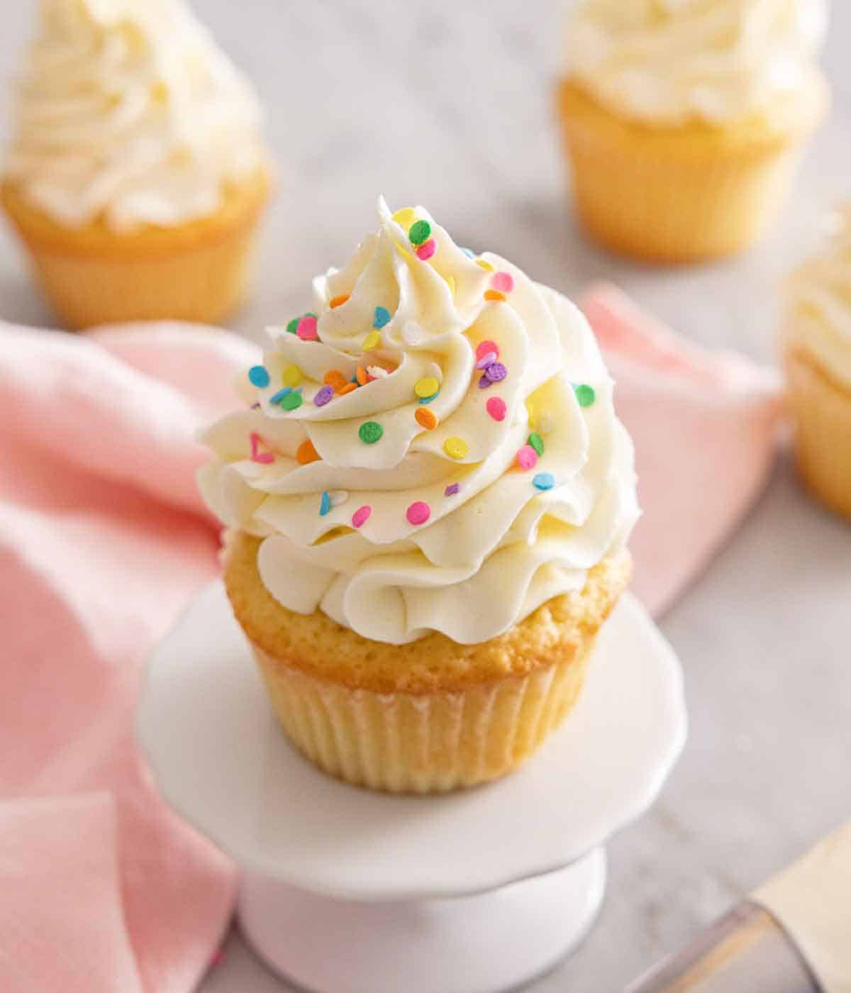 A vanilla cupcake with Swiss meringue buttercream and sprinkles on top.