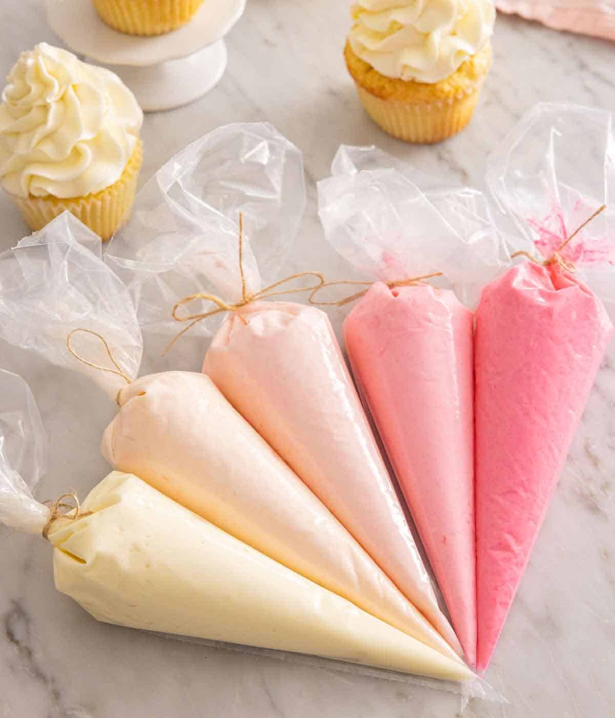 Multiple piping bags filled with colorful Swiss meringue buttercream.