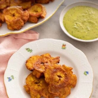 Pinterest graphic of a plate of tostones in front of a platter of more tostones.