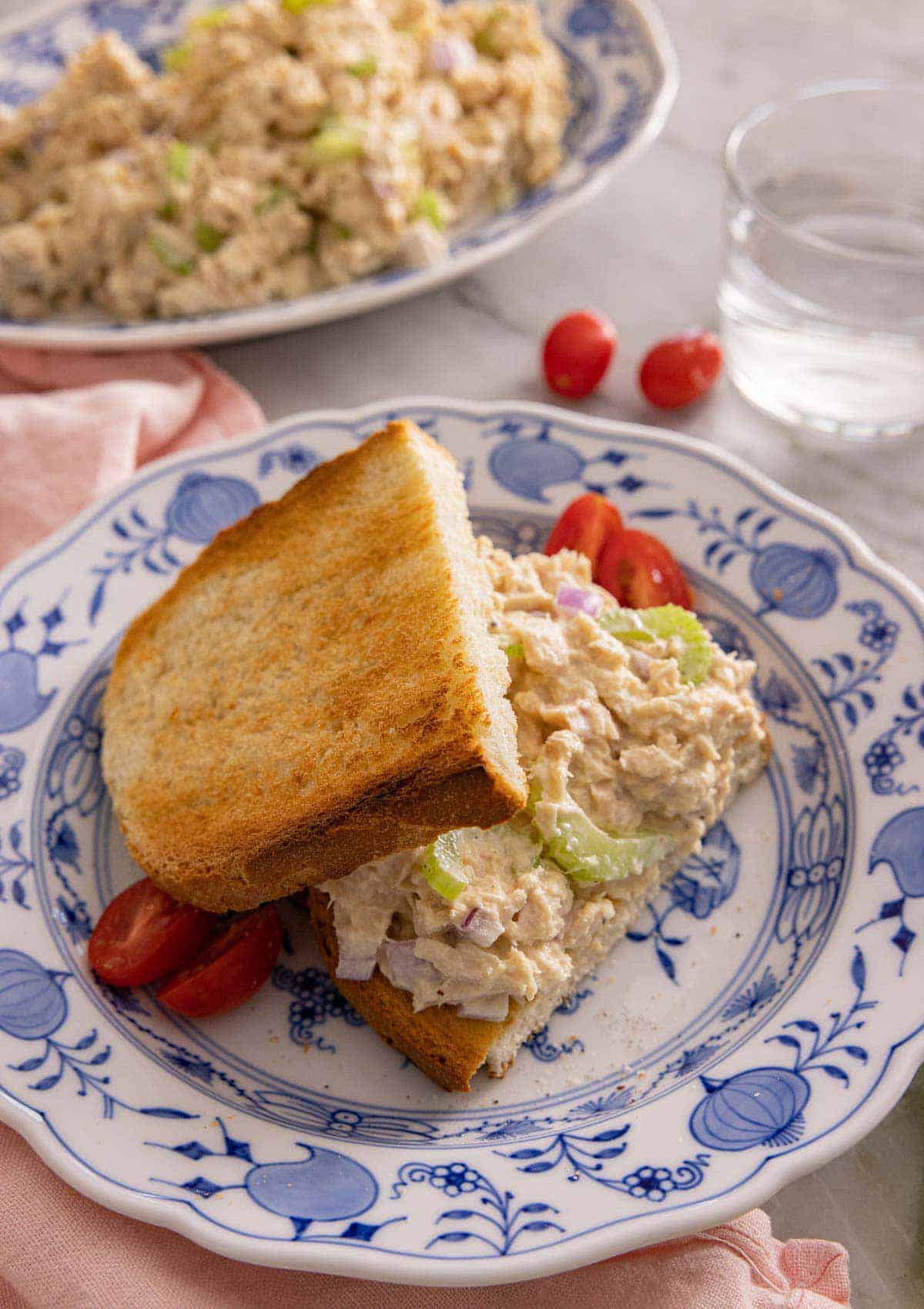Tuna salad on toasted bread on a blue and white plate.
