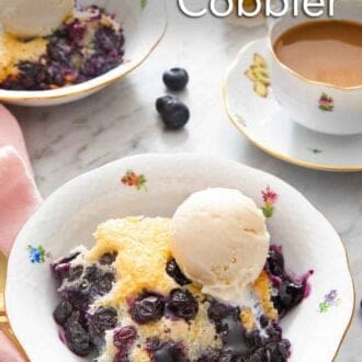 Pinterest graphic of a bowl of blueberry cobbler with a scoop of vanilla ice cream on top by a mug of coffee.