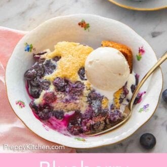 Pinterest graphic of a bowl with blueberry cobbler with ice cream on top and a spoon tucked into the cobbler.