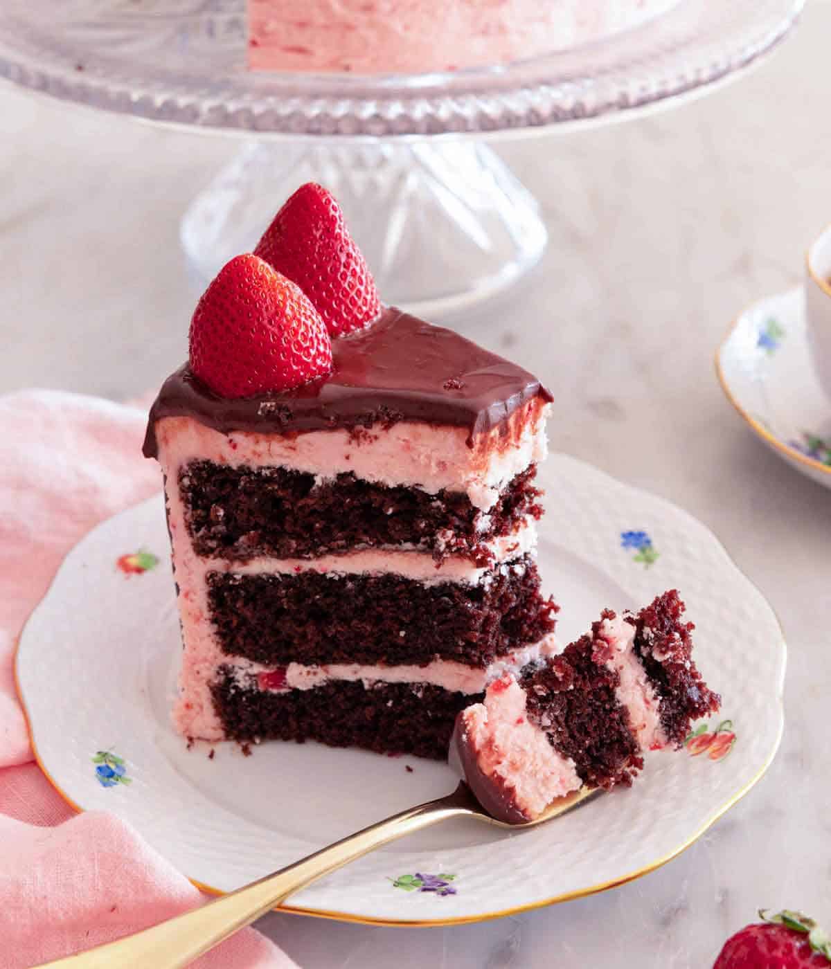 A slice of chocolate strawberry cake with a forkful on the plate.