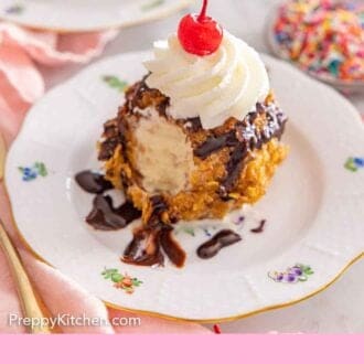 Pinterest graphic of a fried ice cream ball with a bite taken out with whipped cream and a cherry on top.