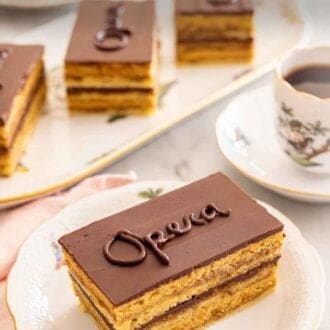 Pinterest graphic of a slice of opera cake on a plate by a mug of coffee and a platter of more cake.