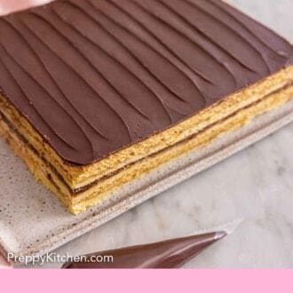 Pinterest graphic of an uncut opera cake with a chocolate piping bag on the side.