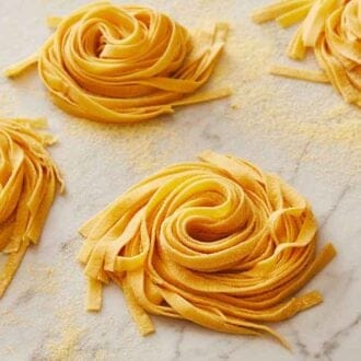 Multiple bundles of pasta dough coated with semolina flour.