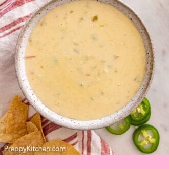 Pinterest graphic of an overhead view of queso dip with sliced jalapeno and tortilla chips beside it.