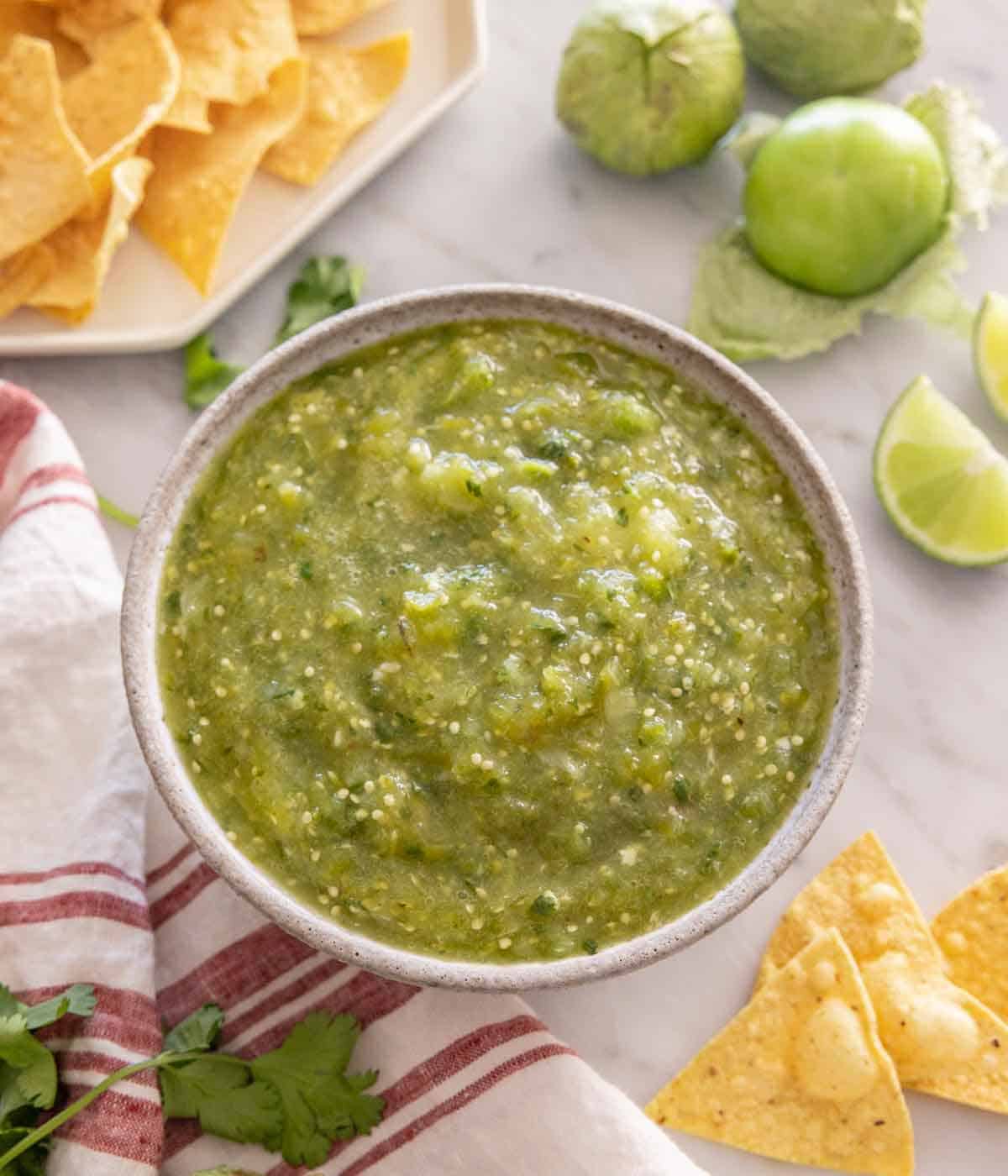 Overhead view of a bowl of salsa verde with ingredients surrounding the bowl.