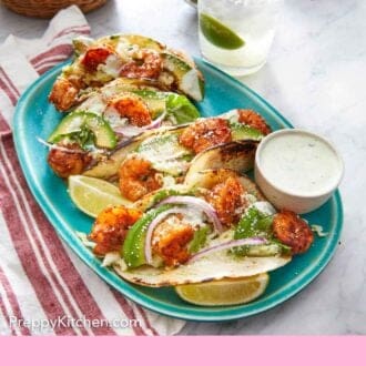 Pinterest graphic of four shrimp tacos on a platter with dip and drink o the side. A basket of tortillas in the background.