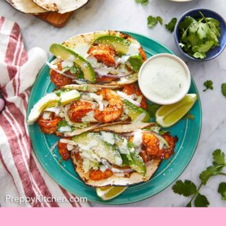 Pinterest graphic of an overhead view of three shrimp tacos with garnishes scattered around.