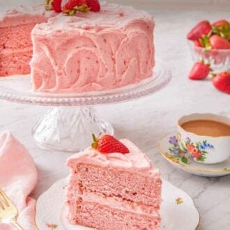 Pinterest graphic a slice of strawberry cake with fresh strawberry on top with the rest of cake in the background.