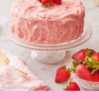 Pinterest graphic of strawberry cake on a cake stand with fresh strawberries on top and on the side.