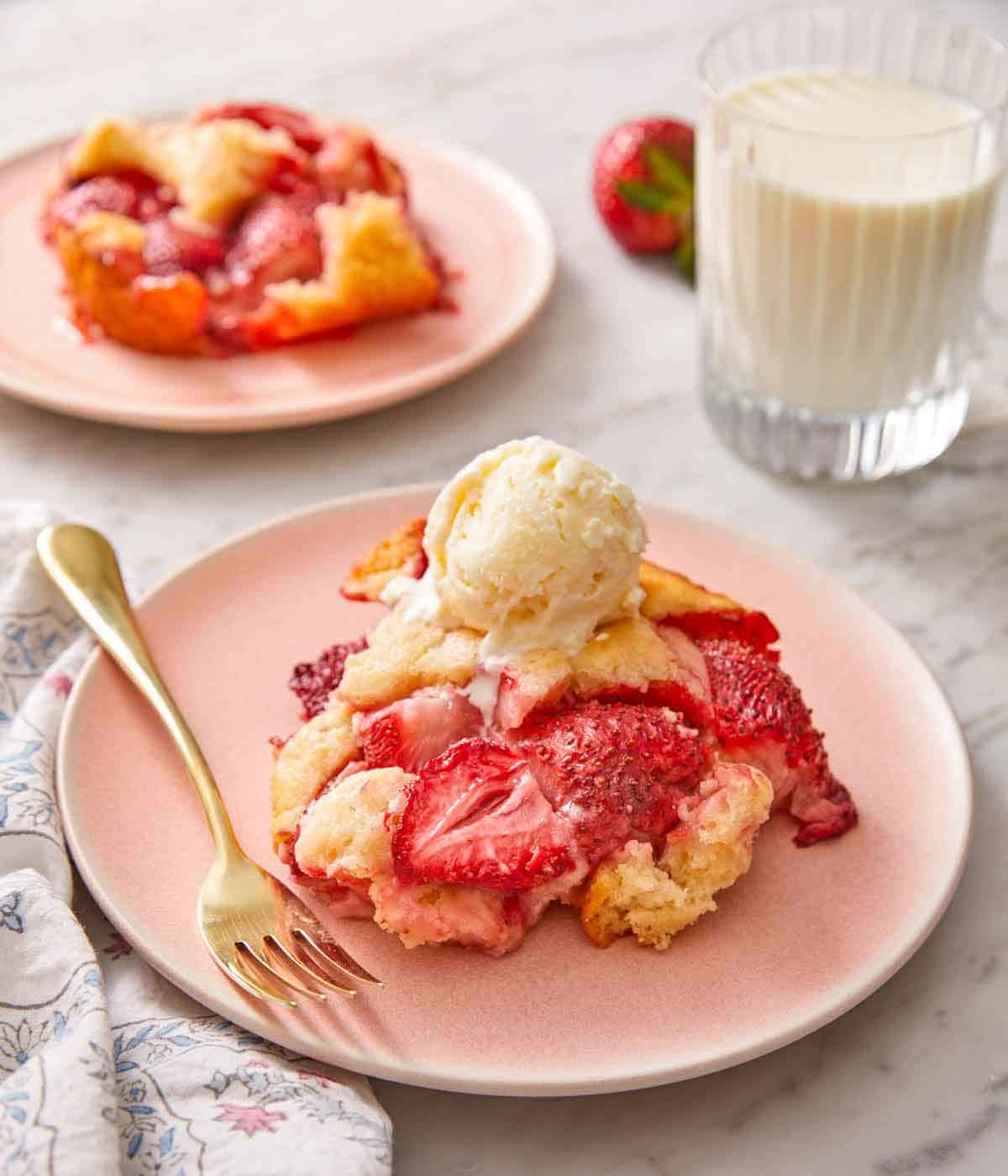 A plate with a serving of strawberry cobbler with a scoop of vanilla ice cream on top.