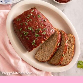Pinterest graphic of an overhead view of a platter of turkey meatloaf that's partway sliced.