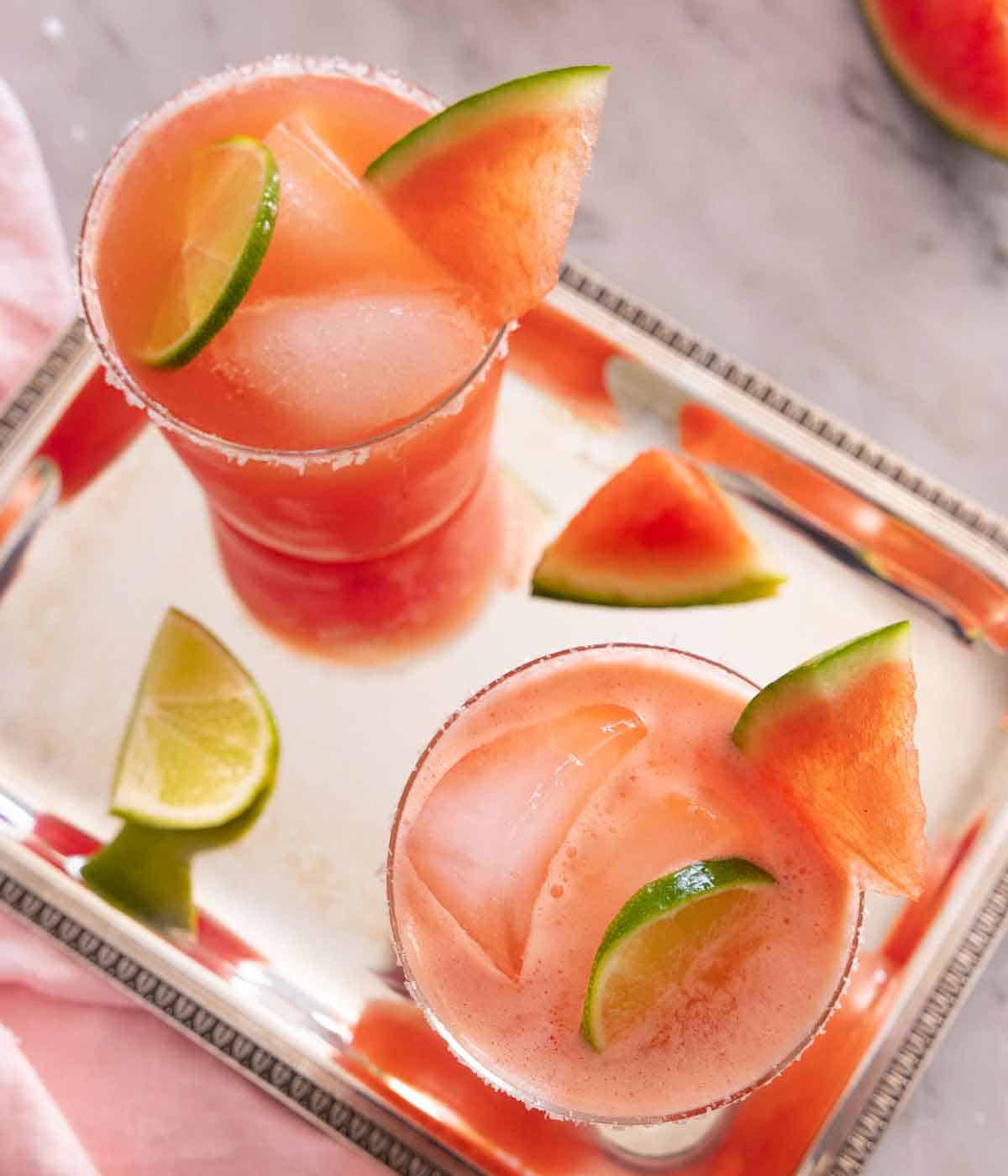 Overhead view of two glasses of watermelon margaritas on a sliver tray.