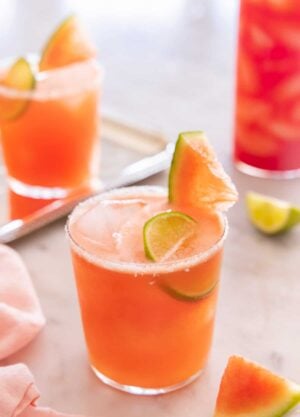 Two short and one tall glass of watermelon margaritas with salt and sliced watermelon on the rim.