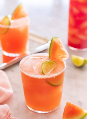 Two short and one tall glass of watermelon margaritas with salt and sliced watermelon on the rim.
