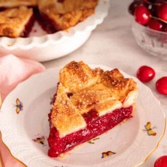 Pinterest graphic of a slice of cherry pie on a plate in front of the rest of the cut pie and fresh cherries.
