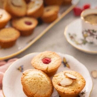 Pinterest graphic of a plate with three financiers, one with a raspberry topping and one with almonds.