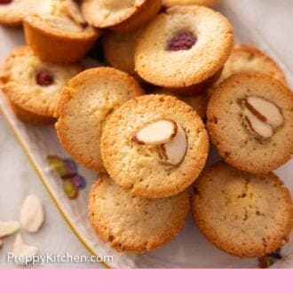 Pinterest graphic a platter of financiers with sliced almonds on top of some and raspberries on top of others.