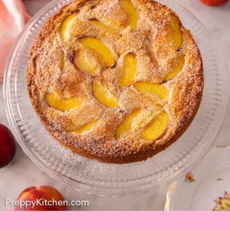 Pinterest graphic of an overhead view of a peach cake with fresh peaches scattered around.