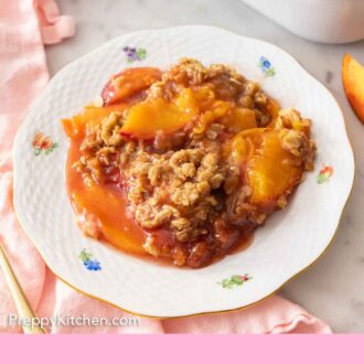 Pinterest graphic of a plate of peach crisp in front of a white baking dish.