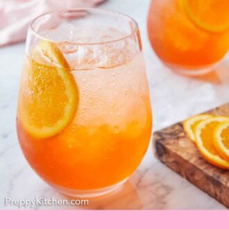 Pinterest graphic of two glasses of aperol spritzes with orange slices inside.