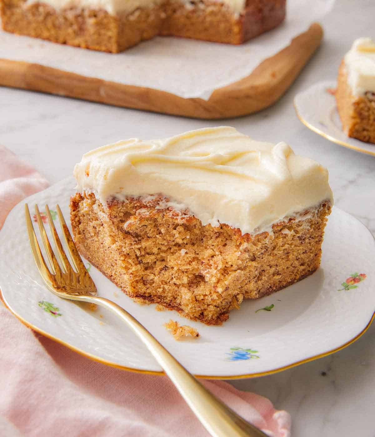 A piece of banana cake on a plate with a fork resting in front.