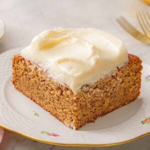 A slice of banana cake with cream cheese frosting on a plate.