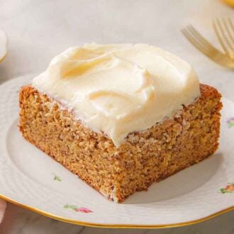 A slice of banana cake with cream cheese frosting on a plate.