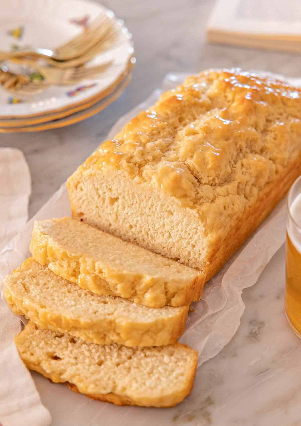 A loaf of beer bread with three slices cut in front of the loaf.