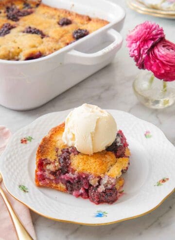 A plate with a serving of blackberry cobbler with a scoop of ice cream on top.