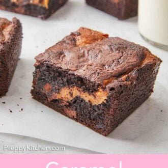 Pinterest graphic of a few caramel brownies on a parchment sheet with one pulled in the front.
