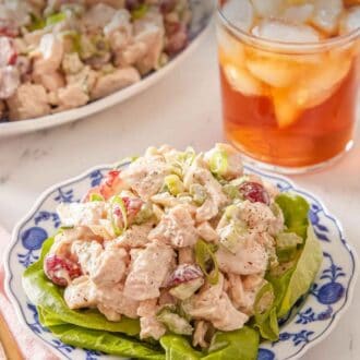 Pinterest graphic of a plate of chicken salad with lettuce underneath with a drink in the background.